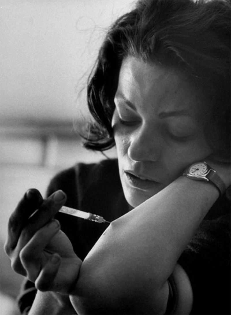 #5 Karen using hypodermic needle on an eyedropper which addict call a “spike” to shoot heroin into vein in her arm.