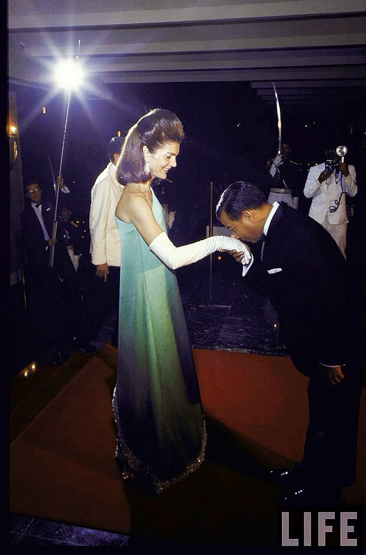 #3 Former First Lady Jacqueline Kennedy graciously accepting kiss on hand fr. Cambodian Prince Norodom Sihanouk during visit. Nov 1967