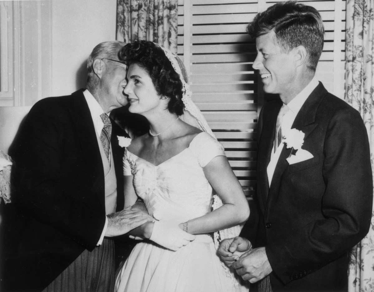 #19 Joseph Kennedy whispers to his new daughter-in-law Jacqueline Bouvier as John F. Kennedy looks on, Newport, Rhode Island, 1953.
