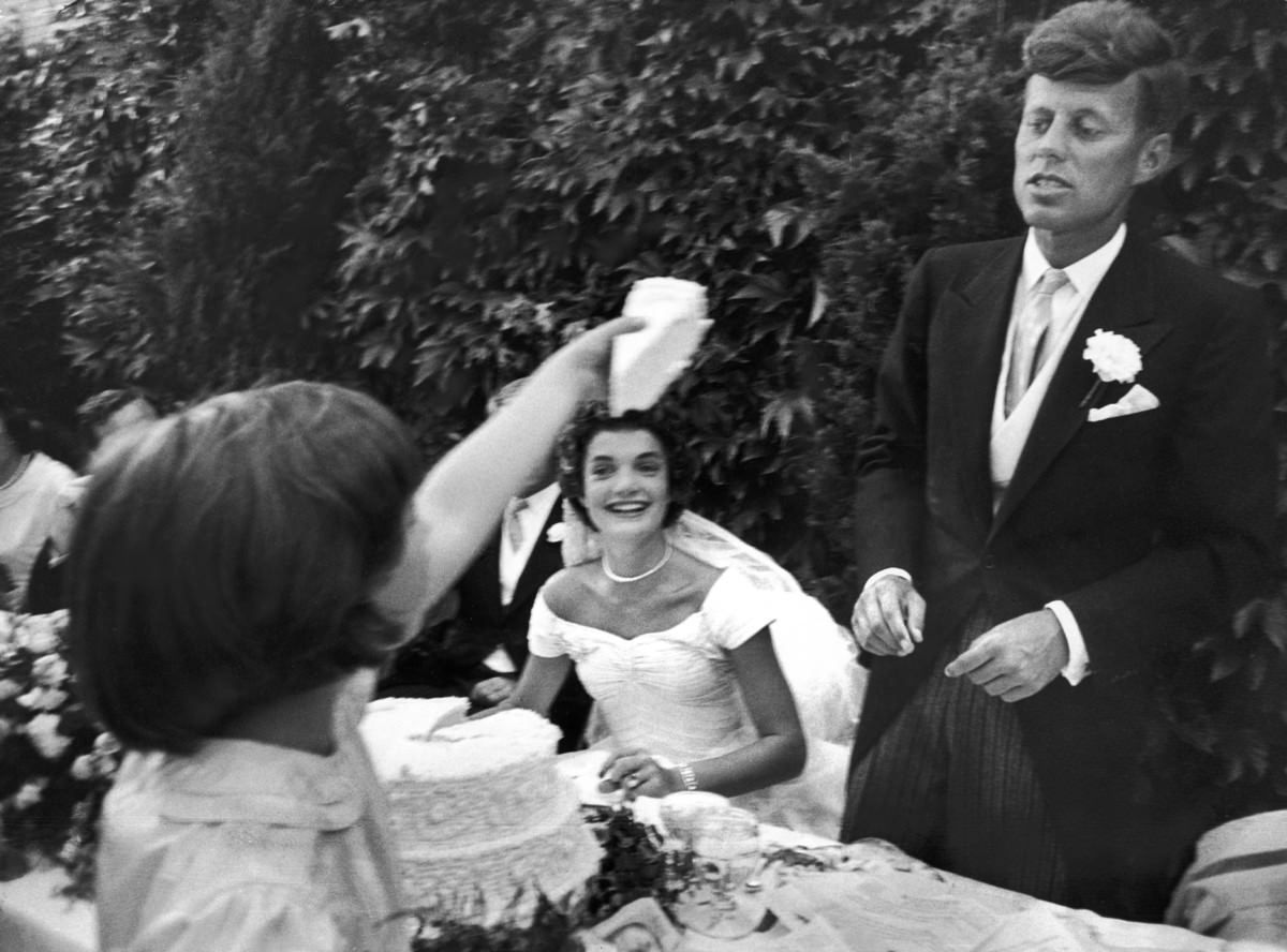 #1 Flower girl Janet Auchincloss holds a piece of wedding cake as Jacqueline Kennedy looks on, 1953.