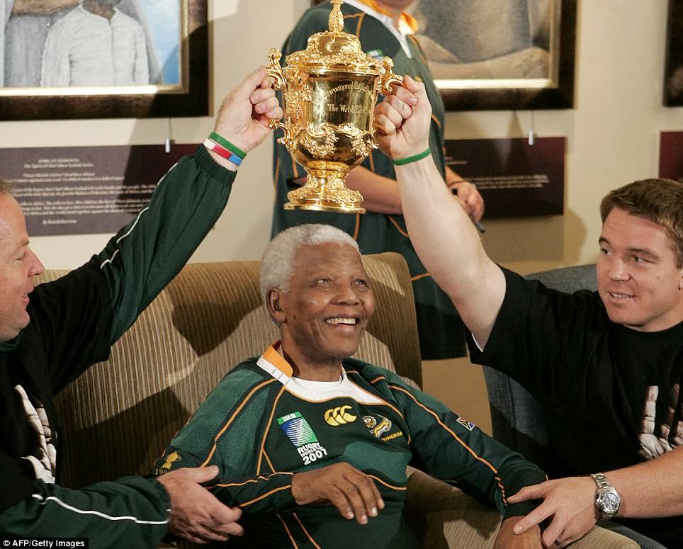 #11 South African president and Nobel peace prize laureate Nelson Mandela (C) poses with the Rugby World Cup held by South African coach Jake White (L) and South African captain John Smit (R) in 2007.