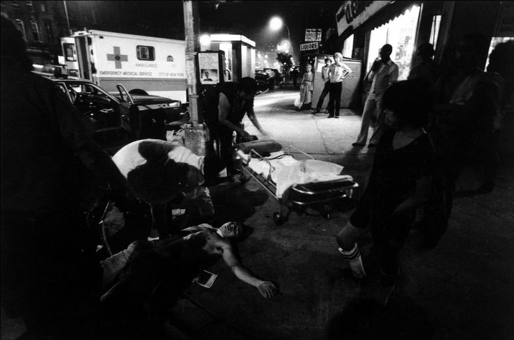 #26 Police and ambulance arrive at the scene of a street fight; a man lies unconscious, 1979.