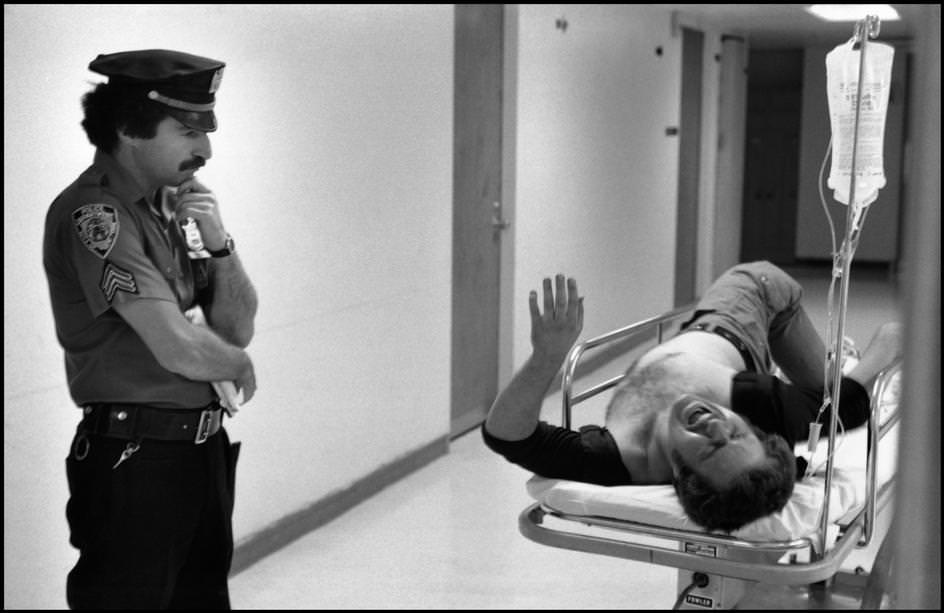 #97 A police officer waits in the hospital waiting room for information on a leg wound victim, 1978.