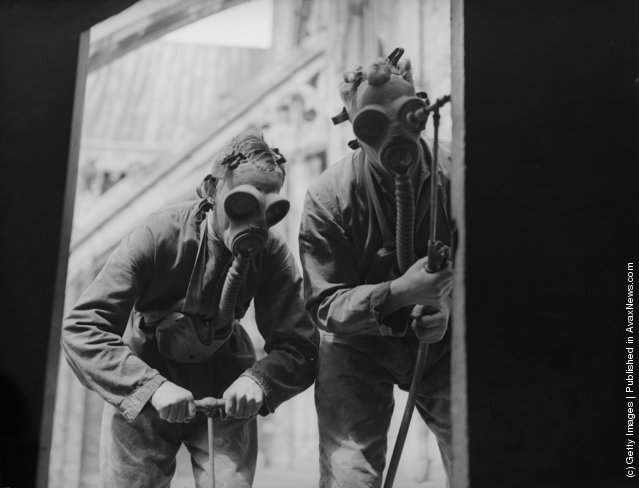 #16 Pest control men in gas masks spraying insecticide around Winchester Cathedral, 1935.