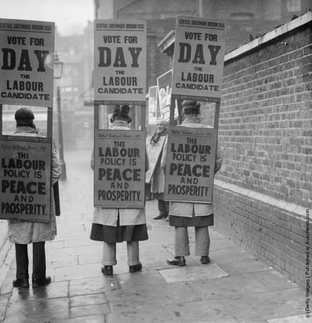 #17 Labour supporters electioneering in gas masks, promoting “Vote Labour,” 1935.