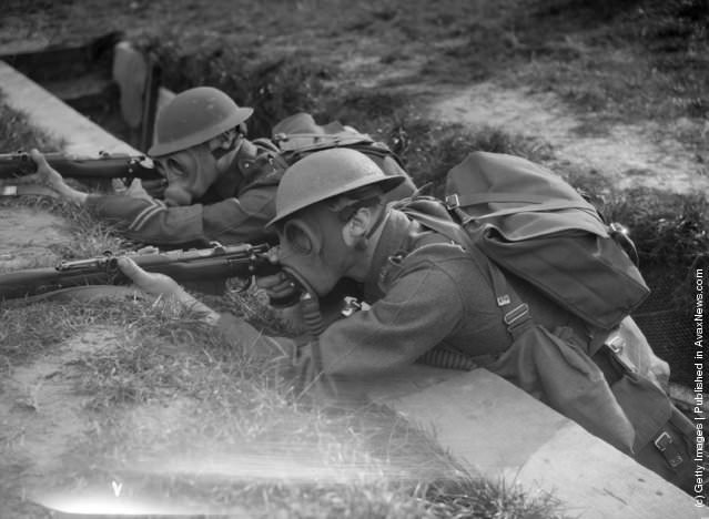#12 Royal Marine recruits practicing trench warfare in gas masks, 1933.