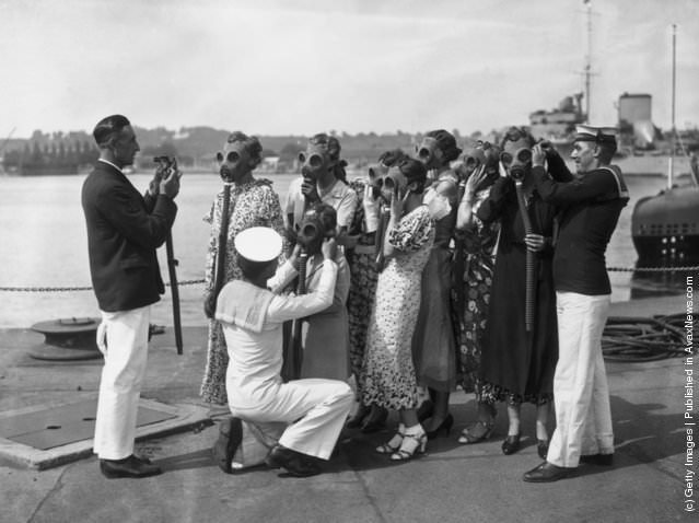 #14 Sailors fitting gas masks on visitors at Chatham, England, during a Navy Week rehearsal, 1935.