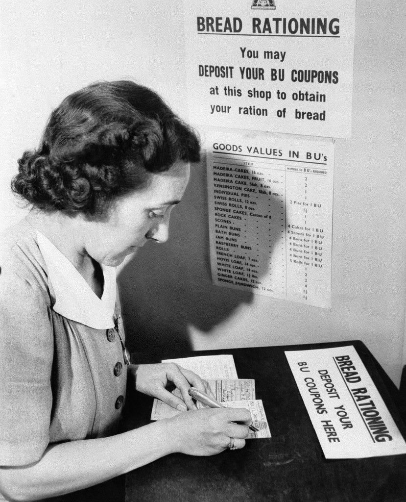 #24 A London housewife fills out her bread unit card in a London shop, 1946.