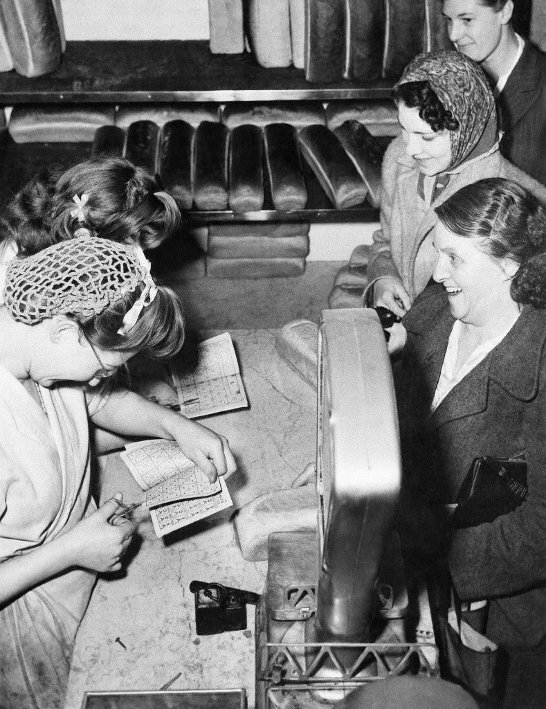 #25 Clerks cut out bread ration coupons before serving customers in a London bakery shop, 1946.