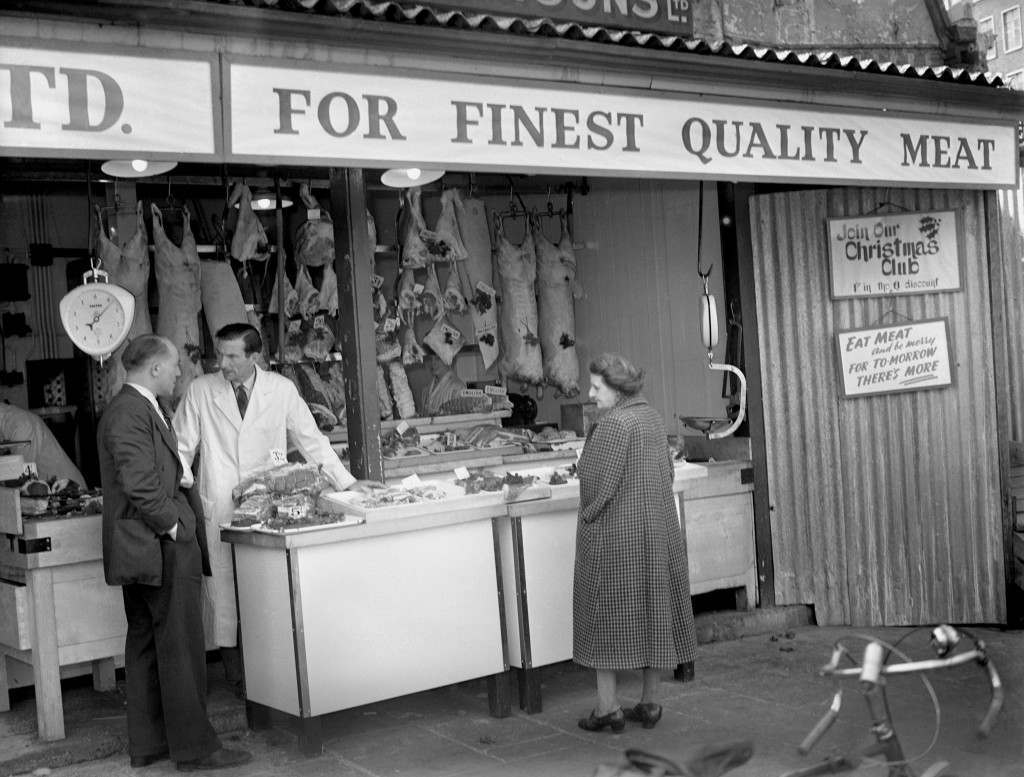 #5 A woman studies meat in a butcher’s shop at Smithfield Market, 1954.