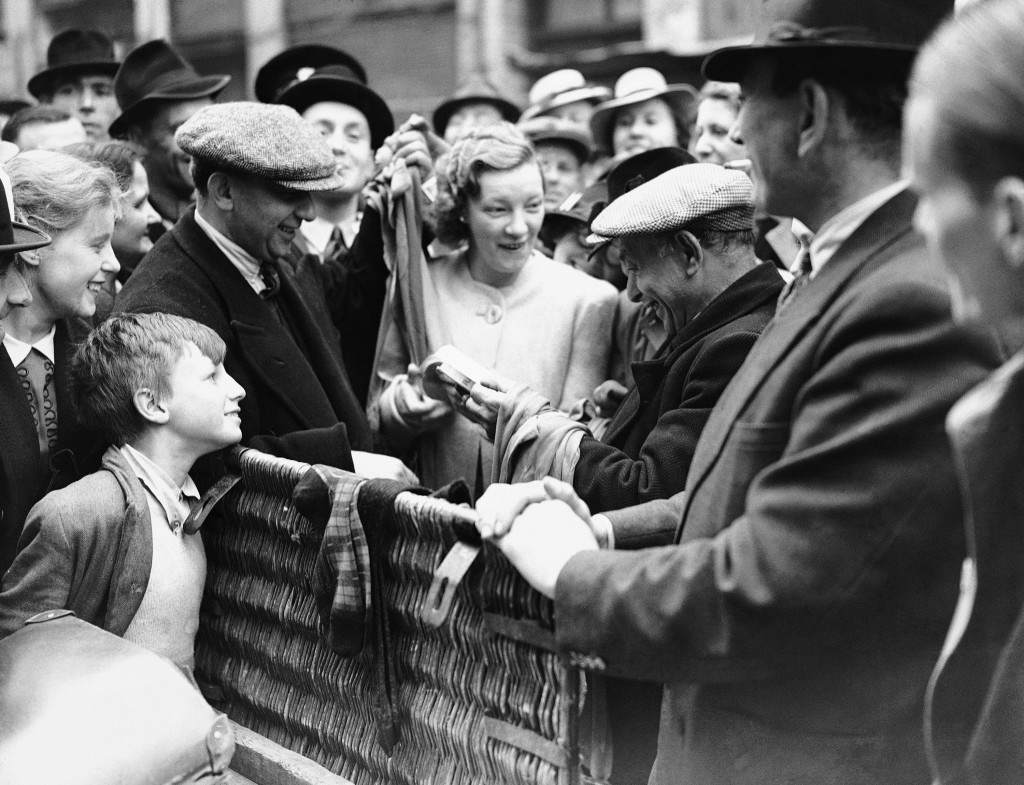 #11 A woman makes a purchase of silk stockings at a stall in London, handing over her coupons, 1941.