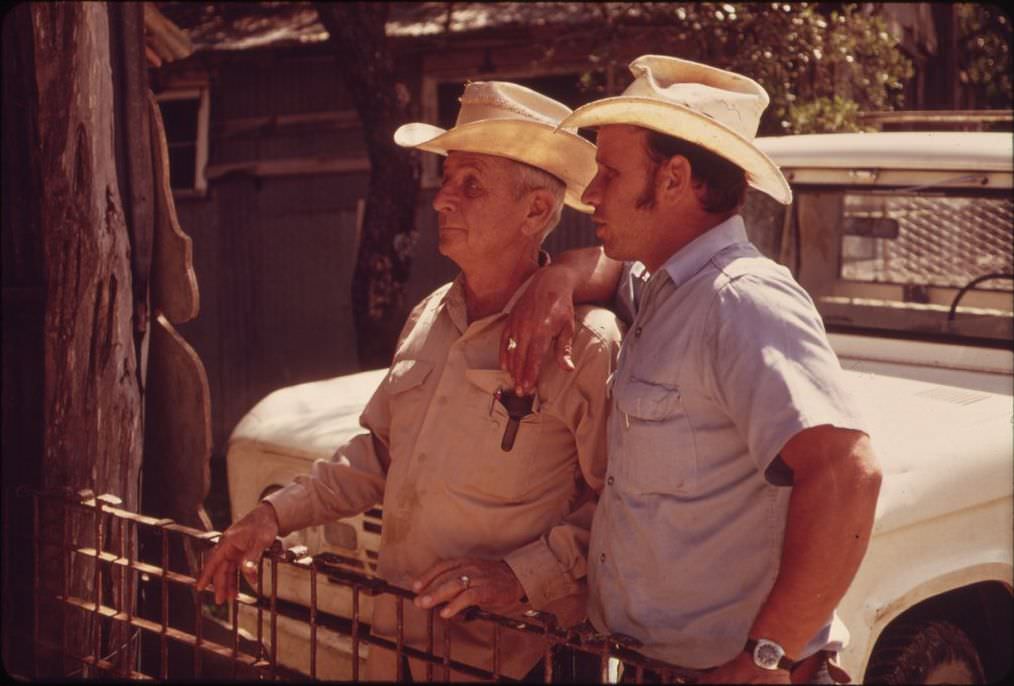 #19 Father and son watching sheep shearing on their ranch near Leakey, Texas, 1973.