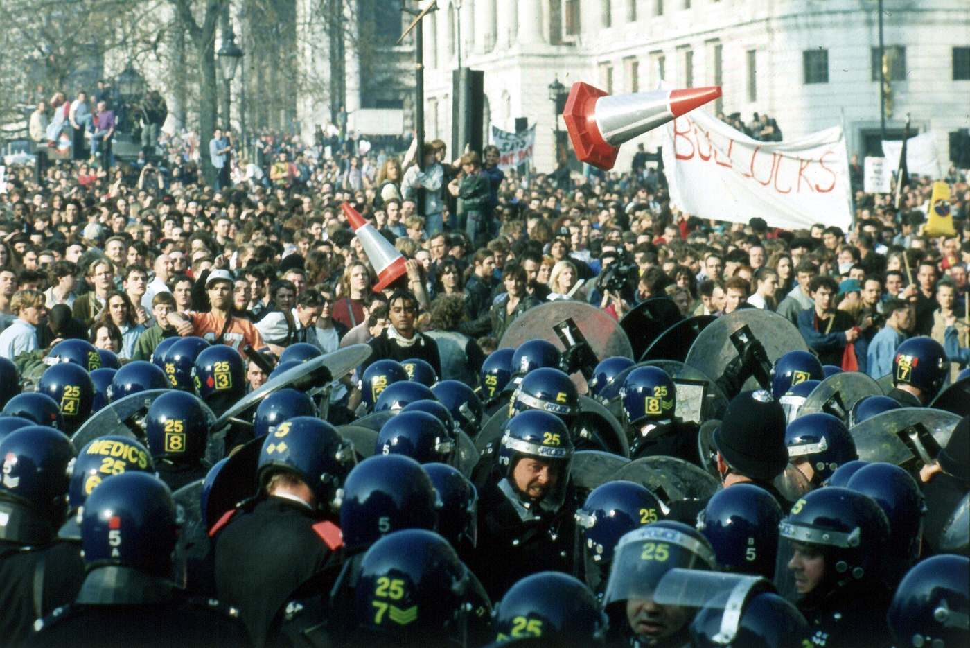 #65 Anti-Poll Tax demonstrators pelting police with missiles in Trafalgar Square, 1990.
