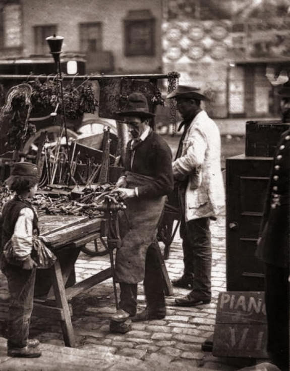 #11 A street locksmith mending locks at his stall, 1877.