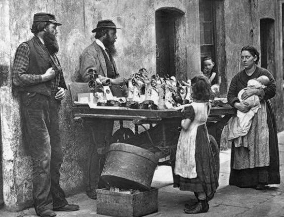 #21 A Victorian fancy wear dealer selling ornaments from his barrow, 1877.