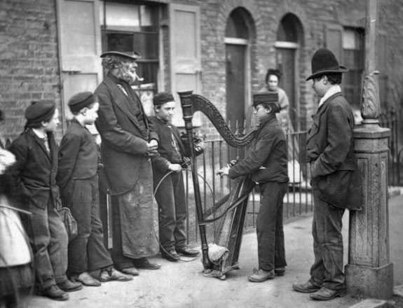 #5 An Italian harpist entertaining children on the street, 1870s.