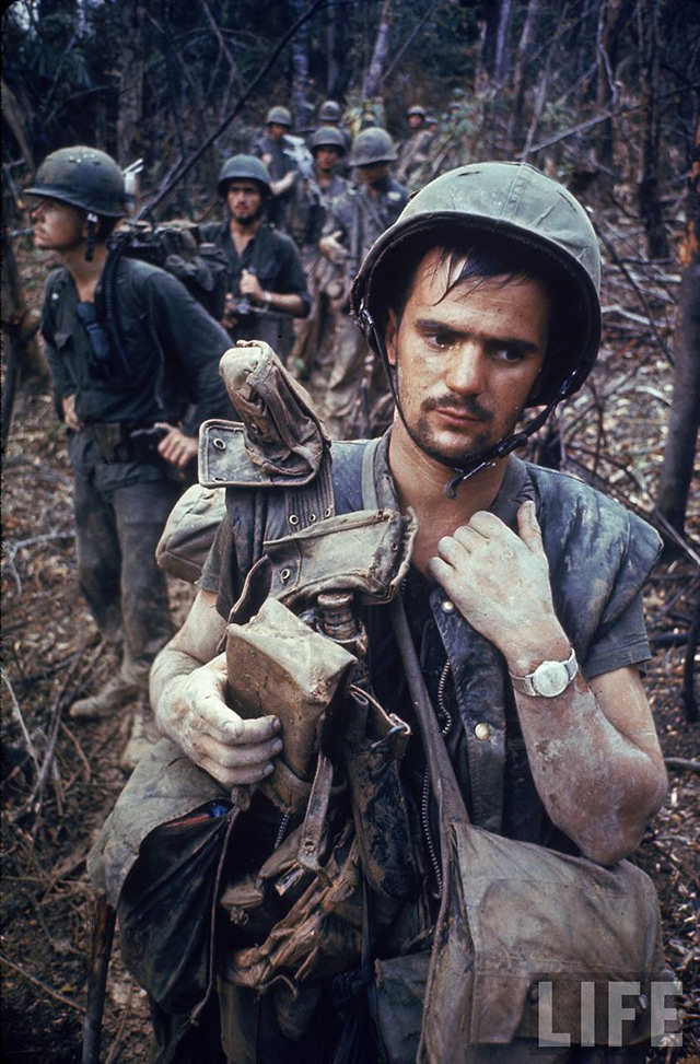 Dirty, exhausted looking US Marine on patrol with his squad near the DMZ during the Vietnam War.