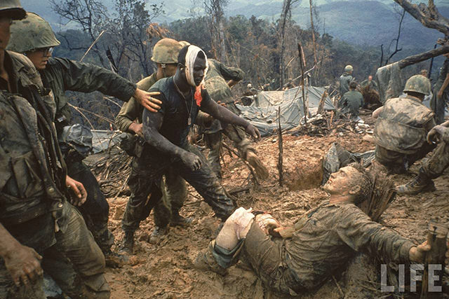 #2 Wounded Marine Gunnery Sgt. Jeremiah Purdie (C) being led past stricken comrade after fierce firefight for control of Hill 484 during the Vietnam war.