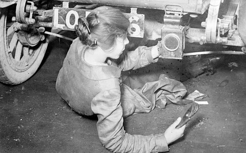 A female mechanic repairs a car, 1917.