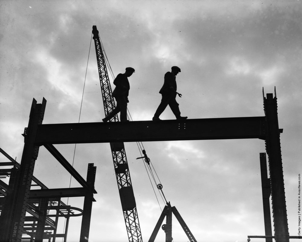 Two workmen walking along a girder during the building of the Freemasons Hospital, Ravenscourt Park, London, 1932.