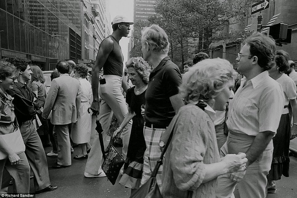 #26 A very tall man towers over other New Yorkers who stare in awe on Fifth Avenue, 1987.