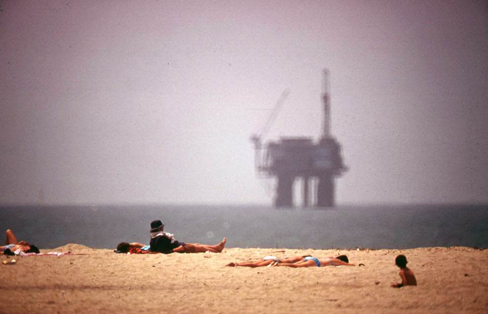 #24 Sunbathers at Huntington Beach, California, with an oil platform visible in the distance, 1975.