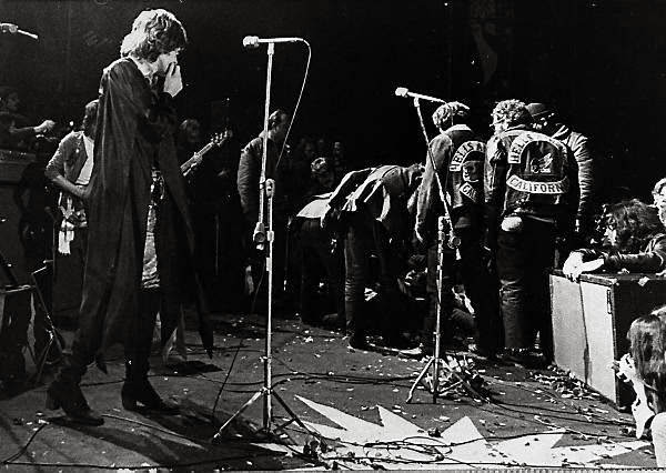 Mick Jagger looks on as the Hells Angels drag their victim’s body onstage during the concert.