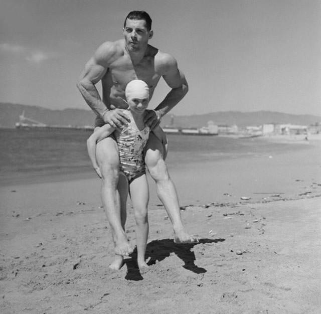 Patricia O’Keefe, a female bodybuilder, gives a 200-pound man a piggyback ride, 1940.