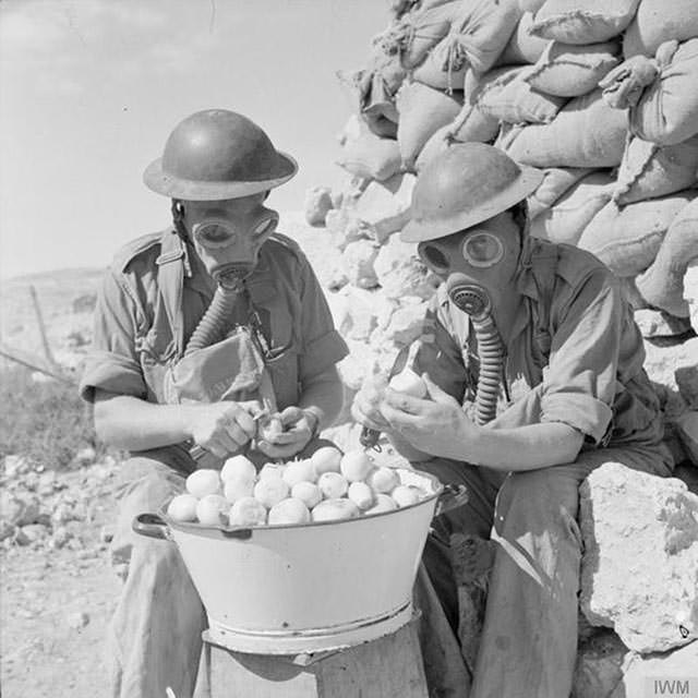 Soldiers using gas masks to stop themselves from crying while peeling onions, 1941.