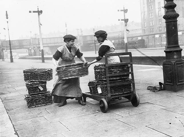 Two women porters at Marylebone station in London loading wicker baskets onto a trolley, 1914.