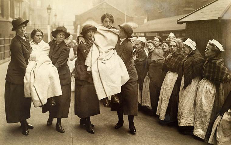 Workhouse women watch female workers demonstrate rescuing skills as part of firefighting training, 1917.