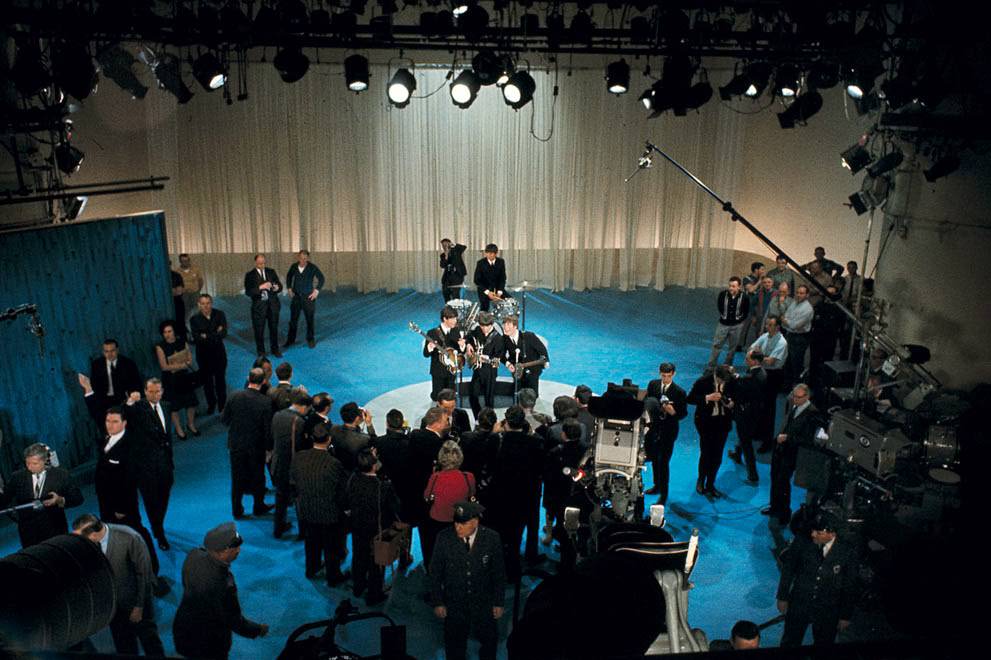 The Beatles surrounded by photographers on stage at CBS’ Studio 50 before their live television appearance on The Ed Sullivan Show in New York City, 1964.