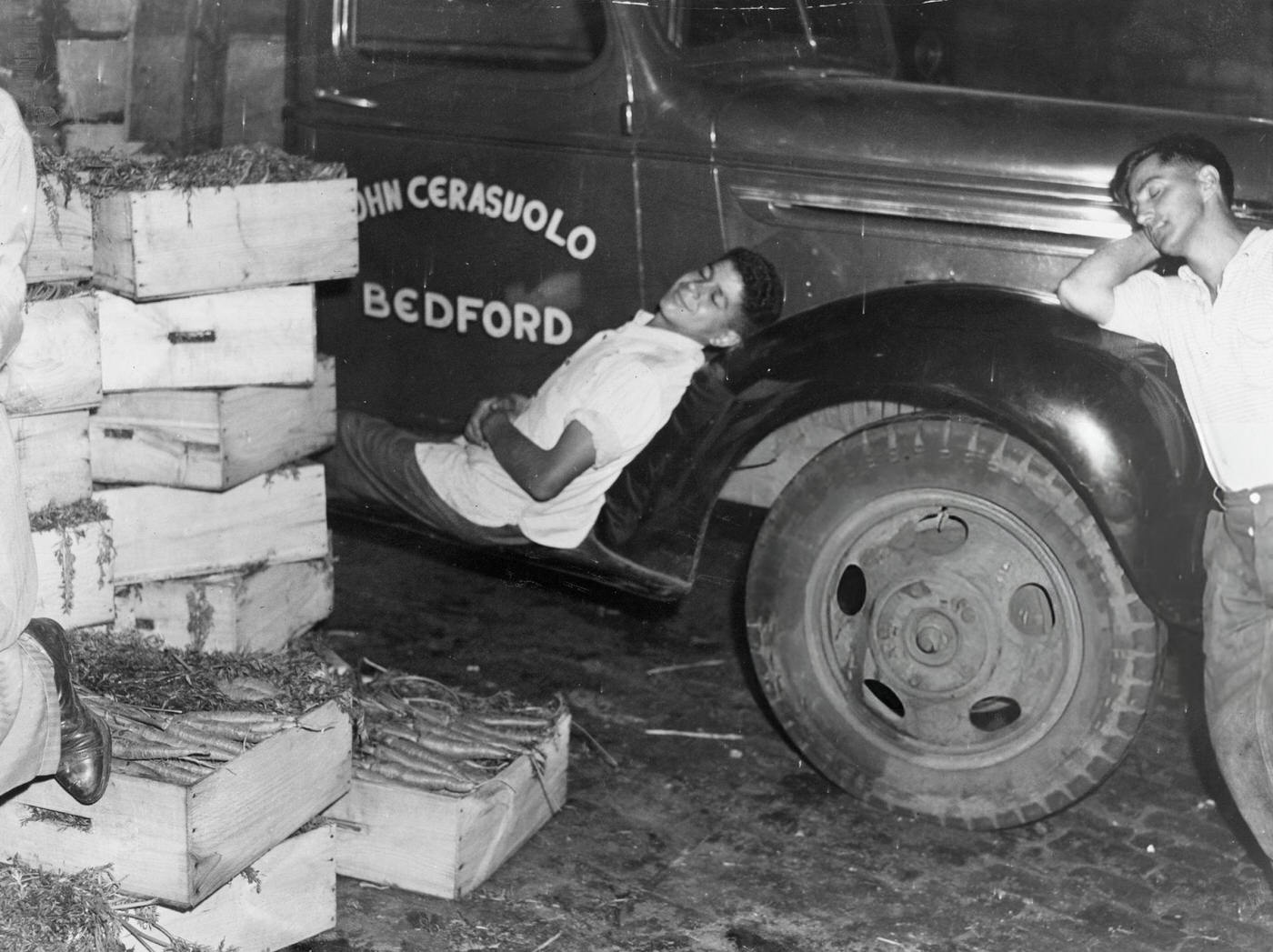 #46 A man sleeps on the side of a truck at the Faneuil Hall Market in Boston, 1940.