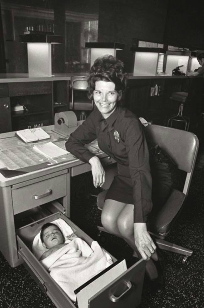 #34 A Los Angeles Police Officer looks after an abandoned baby in the drawer of her desk, 1971.