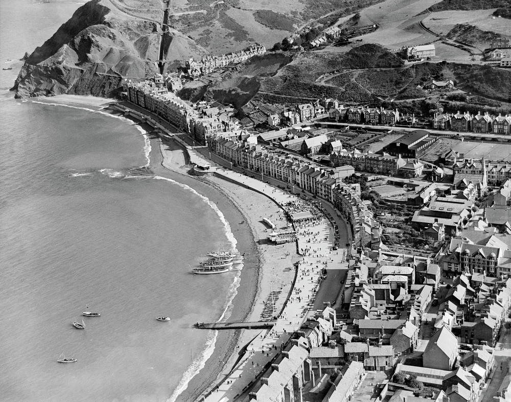 #13 General view of Aberystwyth showing seafront and town in summer, The dignified seafront of Aberystwyth is captured here in the summer of 1932, with pleasure boats moored on the beach ready to take holidaymakers on trips around Cardigan Bay.