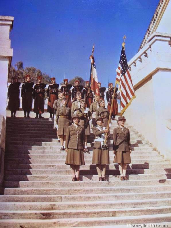 On parade are these WAC’s in North Africa who promenade on the occasion of their review at one of the most historic fortresses in the Mediterranean theatre. The guard of honor is the color guard of the first Zouave Regiment. In the rear are units of three French women in uniform from organizations who join with their American sisters in serving their armies in a vital way.
