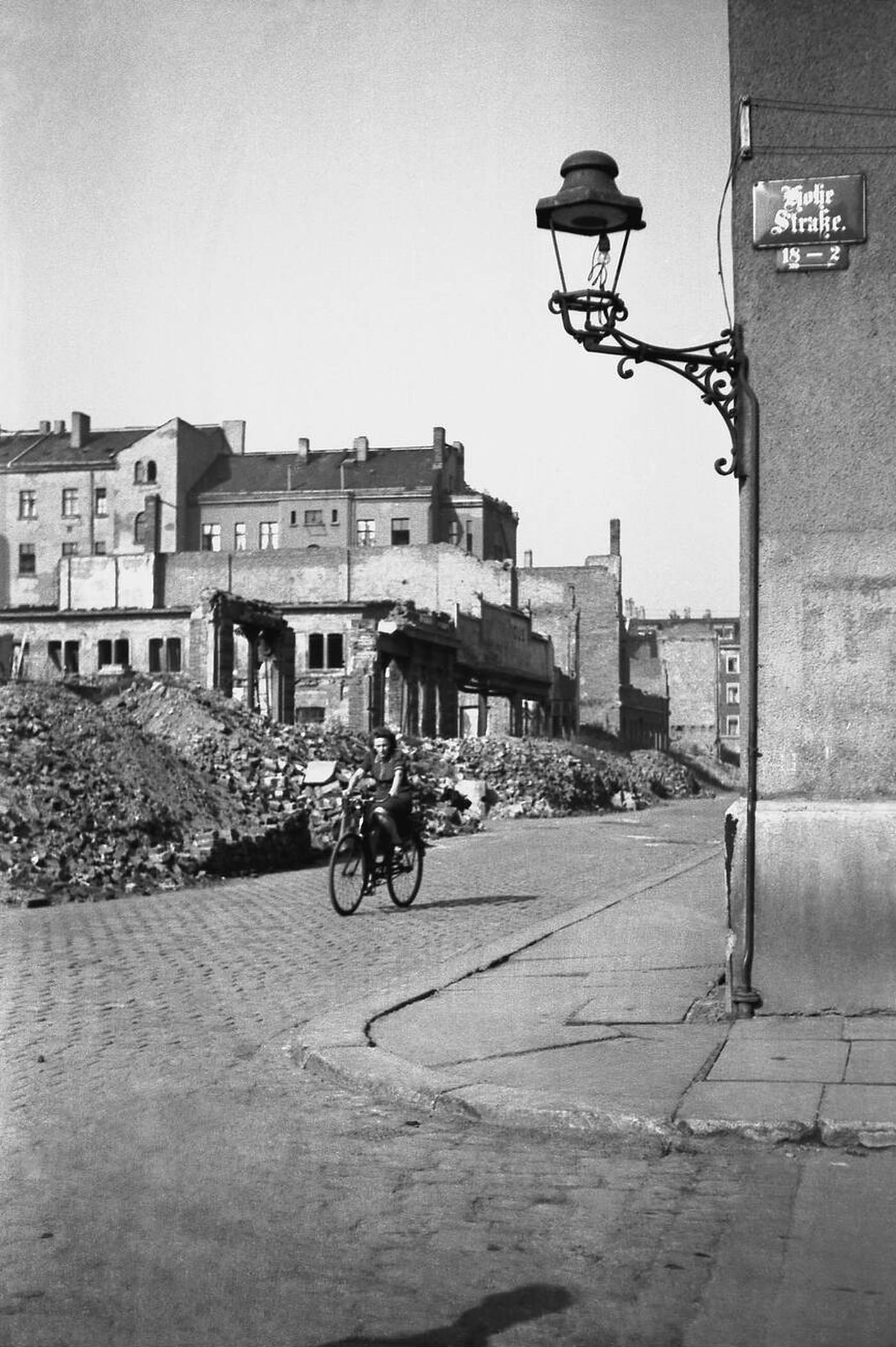 Woman on a bicycle riding through ruins, Leipzig, 1947.