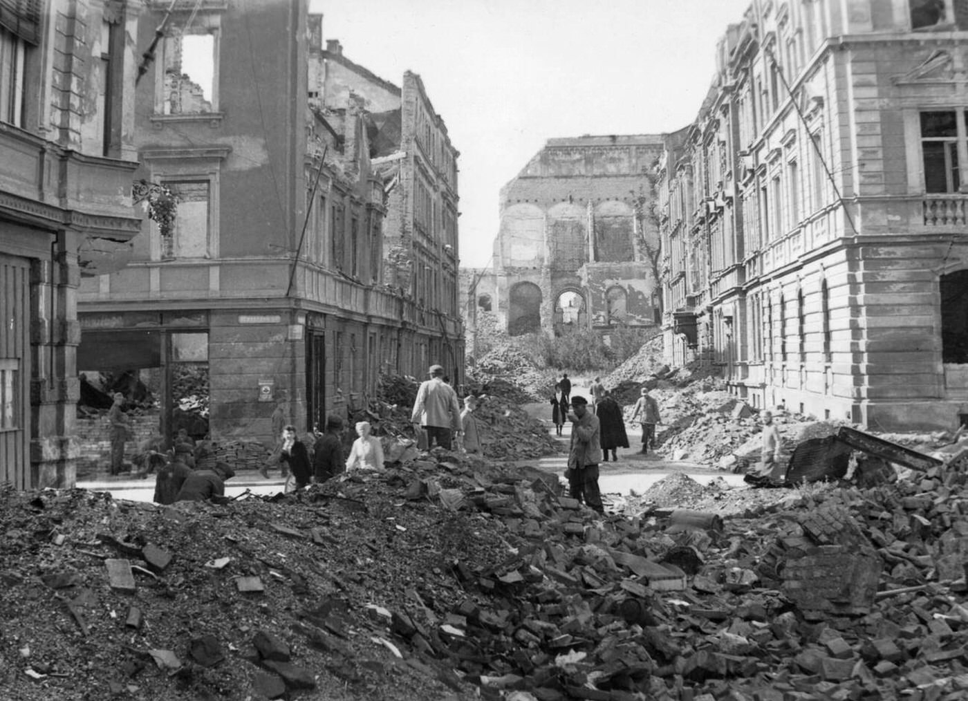 #44 People cleaning up rubble after an Allied bombing at the intersection Schellingstrasse Schraudolphstrasse in Schwabing, Munich; in the background is the destroyed Neue Pinakothek, 1945.