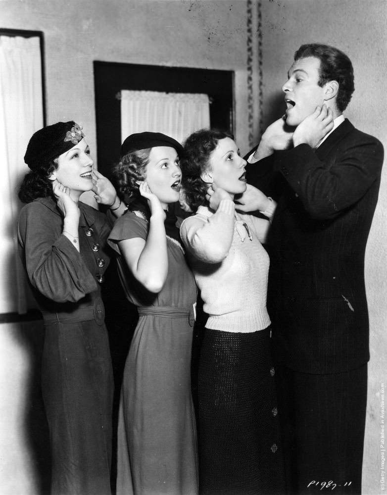 #13 Glenn Erikson teaching Paramount actresses Kay Gordon, Jane Rhodes and Jeanne Perkins how to relax their throats for improved voice control, 1936.