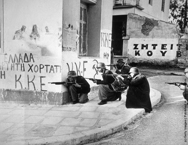 #1 Steel-helmeted Elas troops use a corner building as a shelter as they fire at police headquarters during a civil uprising in Athens, 1944.