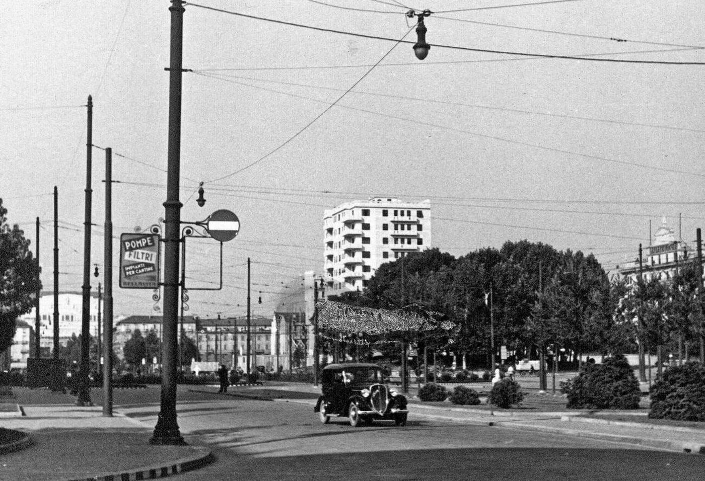 #50 Car driving down street in Milan Italy, 1930s.