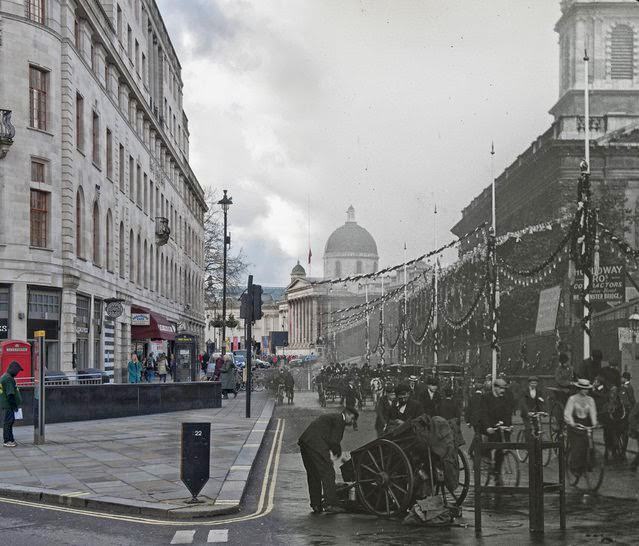 #7 A view of Duncannon Street decorated with bunting and banners for the coronation ceremony of Edward VII. There are pedestrians and vehicles in the foreground and the National Gallery is visible in the distance in 1902 and 2014.