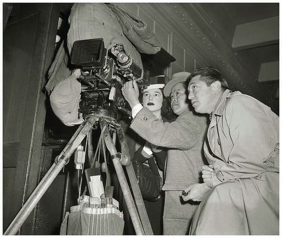James Wong Howe working his cinemagraphic excellence on the film noir “Nora Prentiss” during February, 1946. Actress, Barbara London, and Director, Vincent Sherman, take an interest in James’ viewfinder composition.