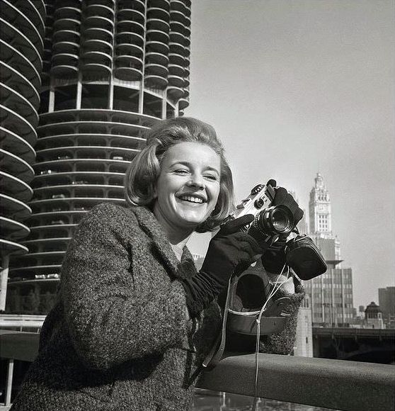 #3 Roberta Woolley, an English actress visiting Chicago, Illinois in March 1964, sports a 35mm Corfield Periflex camera and a Weston Master light meter.
