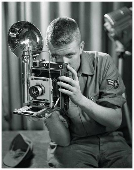 A United States military photographer undergoes training with a large format press camera.