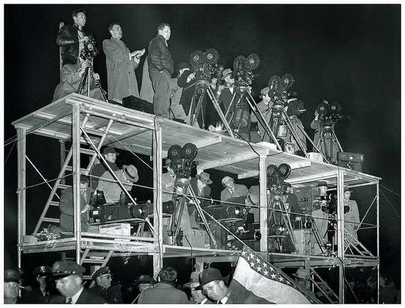 Press and Television corps at MacArthur Day commemorations in Chicago during the late 1940’s. A battery of different cameras, including Arriflex and Mitchell movie cameras, and Graflex ‘Big Bertha’ cameras, are being operated by photographers and cameramen from NBC, and Chicago’s WGN-TV, as well as the Chicago Sun Times.