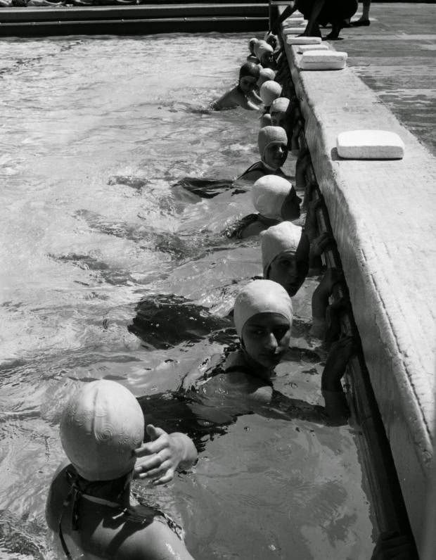 #9 These schoolgirls are clinging to the pool wall, kicking furiously, during a swimming lesson on June 19, 1962.