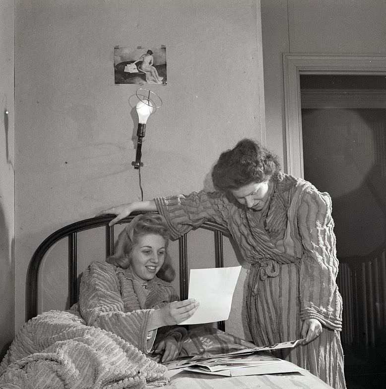 #10 Two girls looking at pictures in their room in a boardinghouse