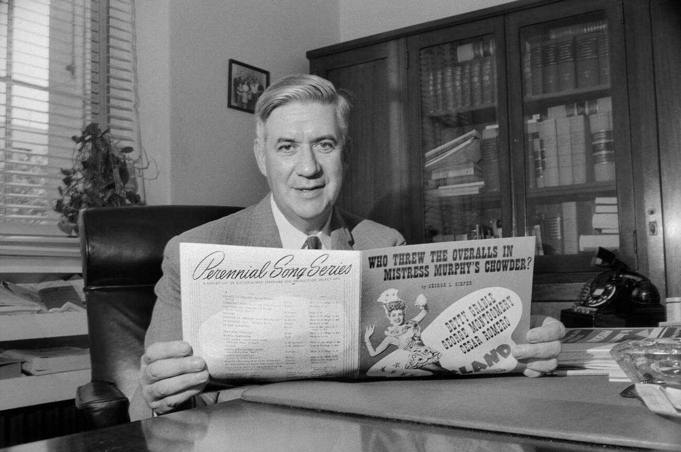 Massachusetts Congressman Thomas P. “Tip” O’Neill sitting at Office Desk and holding Sheet Music, Washington, D.C., 1957.