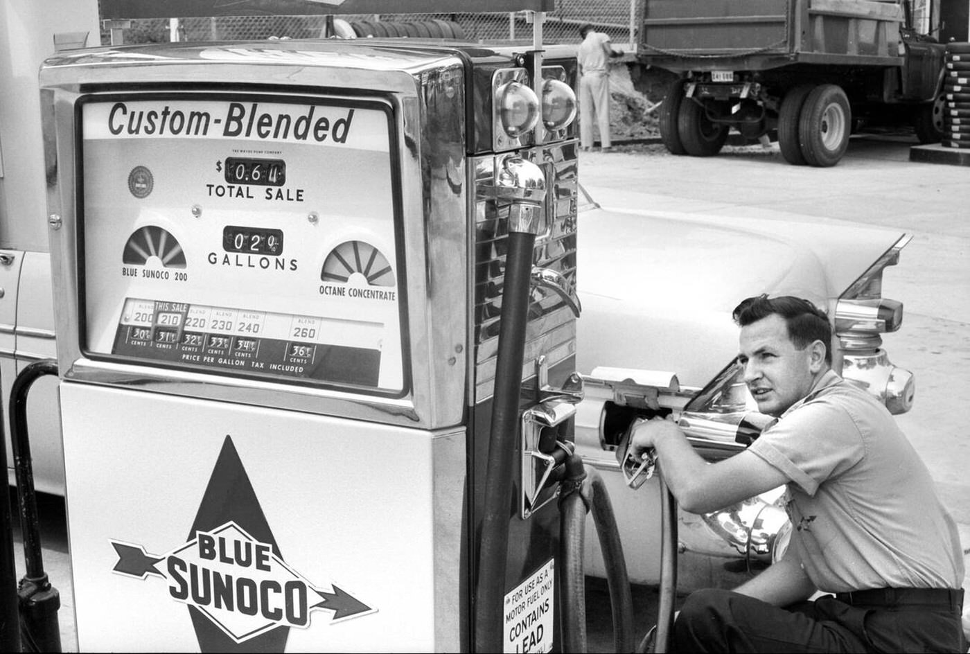 Gas station attendant filling car tank with custom blended gas at Sunoco gas station, Washington, D.C., 1958.